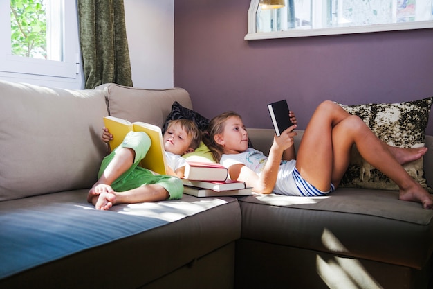 Muchacho y muchacha con los libros en sofá