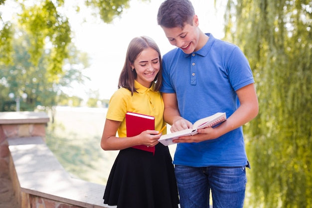 Foto gratuita muchacho que muestra al libro de la muchacha en parque