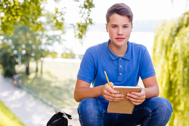 Muchacho que sostiene el cuaderno afuera