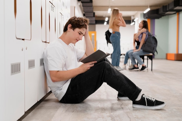 Muchacho de tiro completo leyendo en el piso