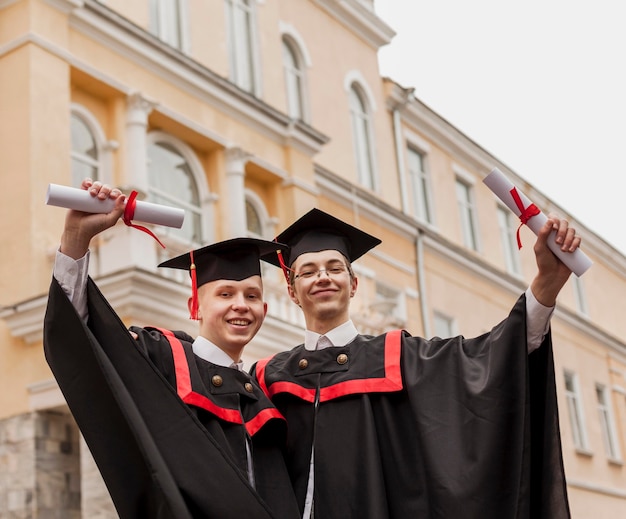 Foto gratuita muchachos de ángulo bajo con diploma