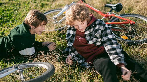 Muchachos sonrientes relajándose sobre el césped mientras andan en bicicleta