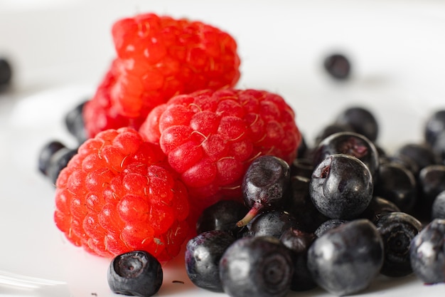 Muchas bayas de frambuesa rojas maduras frescas jugosas con moras aislado sobre fondo blanco.