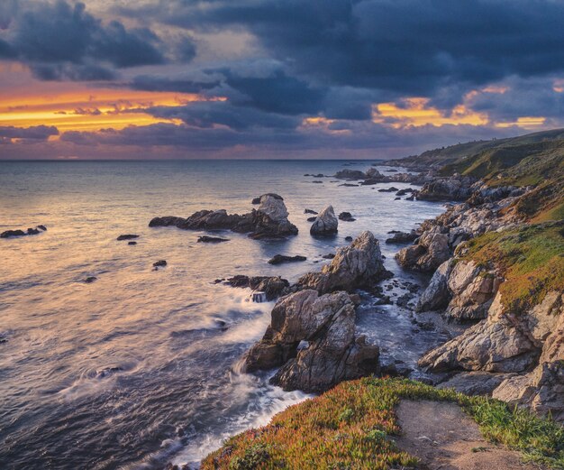 Muchas formaciones rocosas cubiertas de musgo cerca del mar bajo el cielo del atardecer