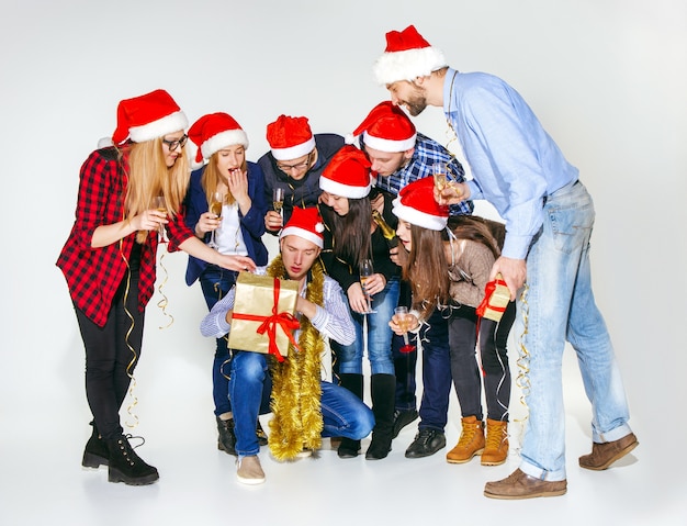 Muchas mujeres y hombres jóvenes bebiendo en la fiesta de Navidad en estudio blanco