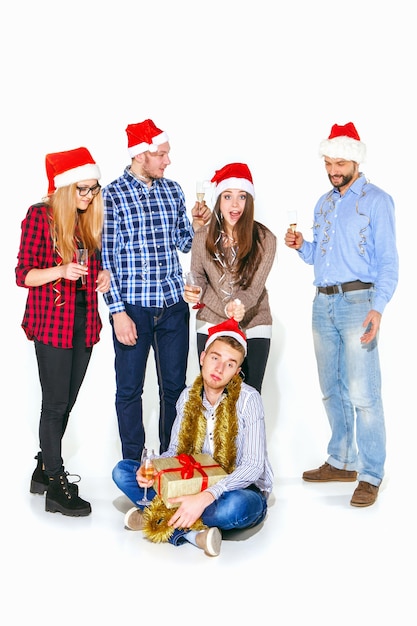 Muchas mujeres y hombres jóvenes bebiendo en la fiesta de Navidad en estudio blanco