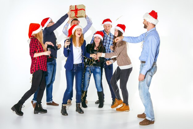 Muchas mujeres y hombres jóvenes bebiendo en la fiesta de Navidad sobre fondo blanco de estudio