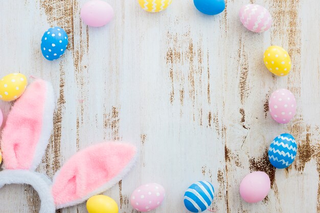 Muchos huevos de Pascua con orejas de conejo en mesa de madera