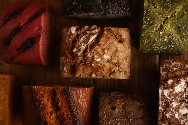 Muchos panes horneados alternativos mixtos presentados para la venta en una mesa de madera rústica en una panadería profesional hecha de pistacho