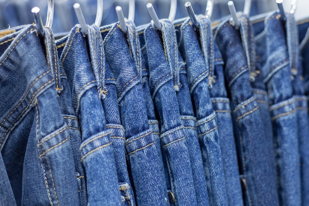 Muchos pantalones vaqueros de mezclilla colgando en un estante | Foto