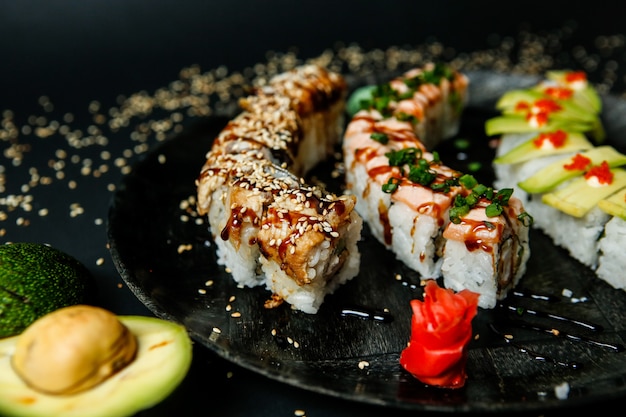 Muchos tipos diversos de rollos de sushi cubiertos con semillas de sésamo vista cercana