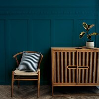 Foto gratuita mueble escandinavo de madera vintage con silla junto a una pared azul oscuro
