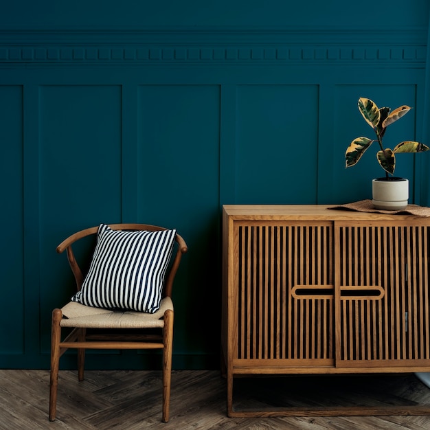 Mueble escandinavo de madera vintage con silla junto a una pared azul oscuro