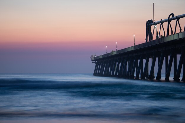 Muelle cerca del mar en calma bajo el hermoso cielo al atardecer