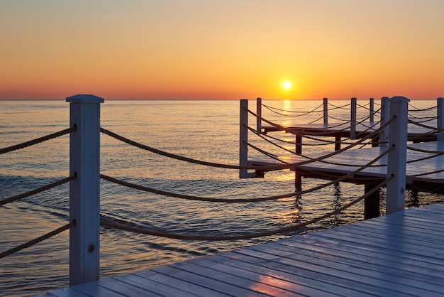 Muelle de madera en una elegante puesta de sol naranja.