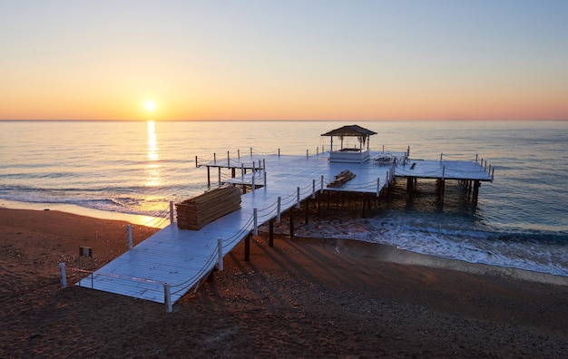 Muelle de madera en una elegante puesta de sol naranja.