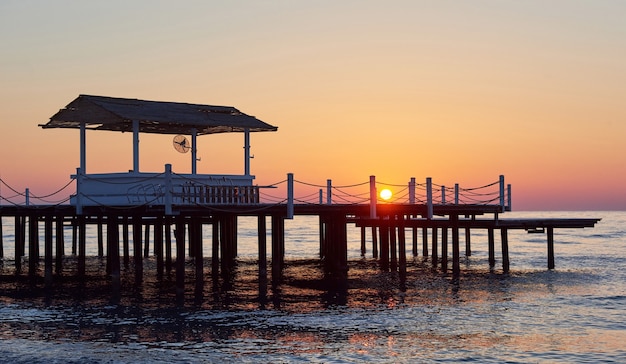 Muelle de madera en una elegante puesta de sol naranja.