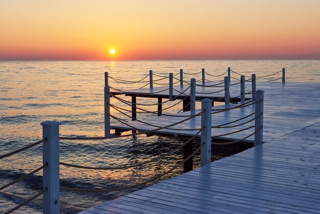 Muelle de madera en una elegante puesta de sol naranja.