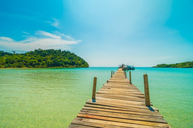 Muelle de madera o puente con playa tropical y mar en isla paradisíaca