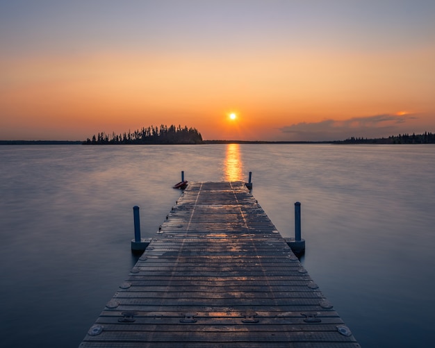 Muelle de madera vacía en un lago durante una impresionante puesta de sol, un fondo fresco