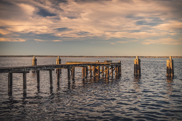 Muelle de madera vieja en el mar bajo la luz del sol durante la puesta de sol