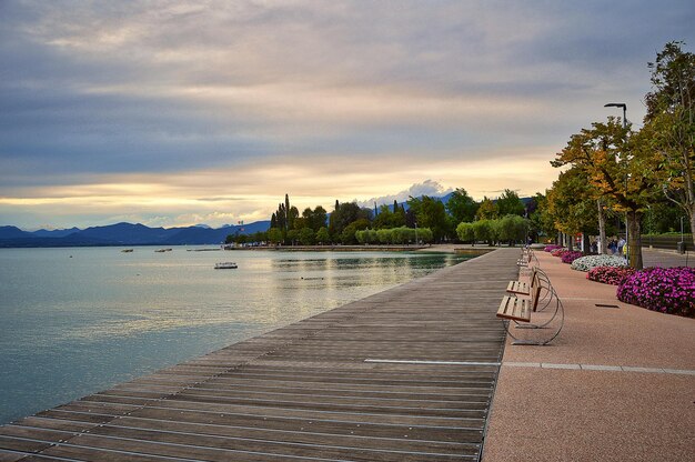 Muelle de paseo de Bardolino, lago de Garda con bancos, flores, árboles, agua y espectacular cielo nocturno