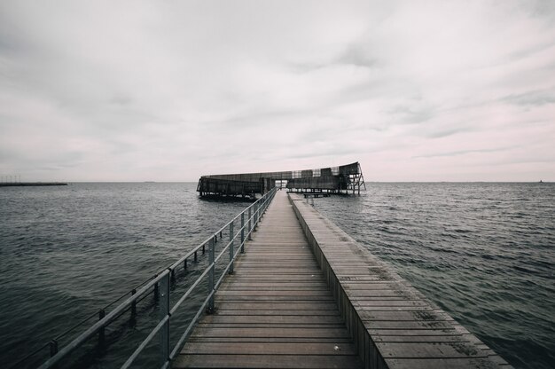 Muelle que conduce al océano bajo el cielo sombrío