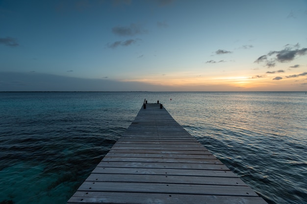 Muelle que conduce a la impresionante puesta de sol que se refleja en el océano en Bonaire, Caribe