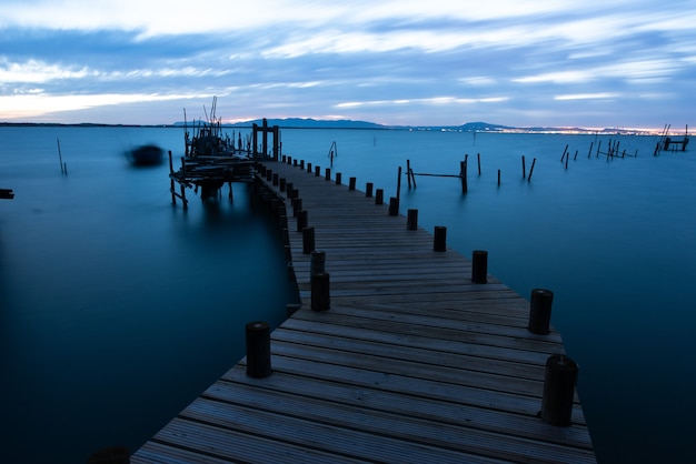 Muelle sobre el mar rodeado de colinas bajo un cielo nublado por la noche en Portugal