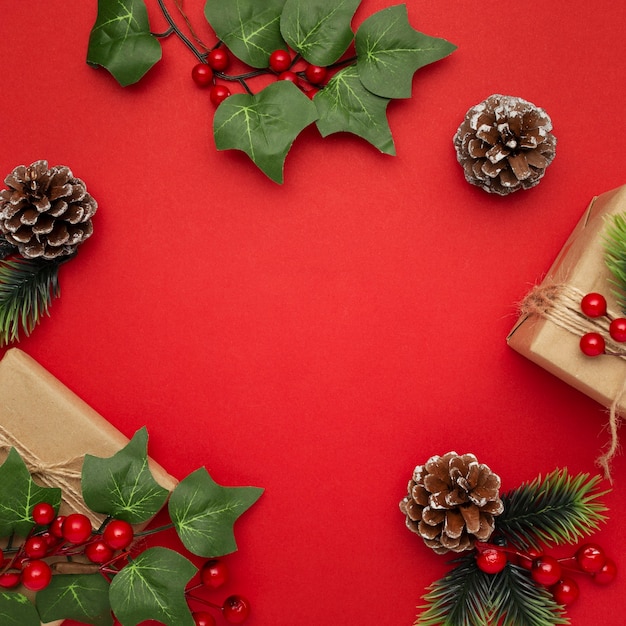 Muérdago, piñas y regalos de Navidad en mesa roja
