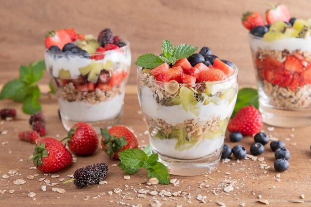 Muesli casero, tazón de granola de avena con yogur, arándanos frescos, moras, fresas, kiwi, menta y nueces para un desayuno saludable, copie el espacio. Concepto de desayuno saludable. Comer limpio.