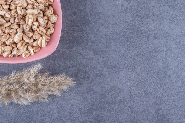 Muesli dulce en un cuenco junto a la hierba de la pampa, sobre la mesa azul.