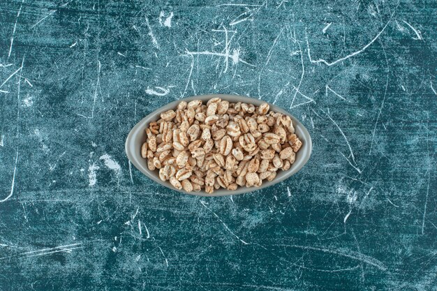 Muesli dulce en un cuenco, sobre el fondo azul. Foto de alta calidad