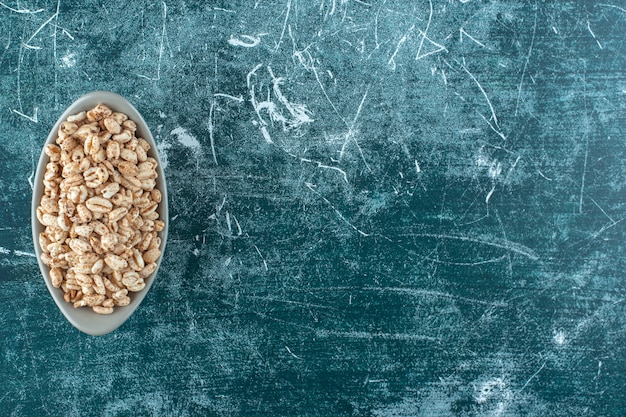 Muesli dulce en un cuenco, sobre la mesa azul.