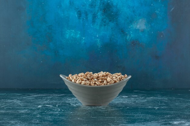 Muesli dulce en un cuenco, sobre la mesa azul.