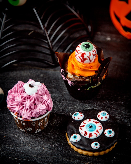 Foto gratuita muffin de chocolate con crema de naranja y galletas de halloween