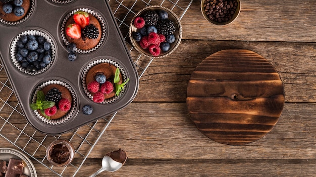 Foto gratuita muffin sabroso endecha plana con frutos del bosque en bandeja para hornear