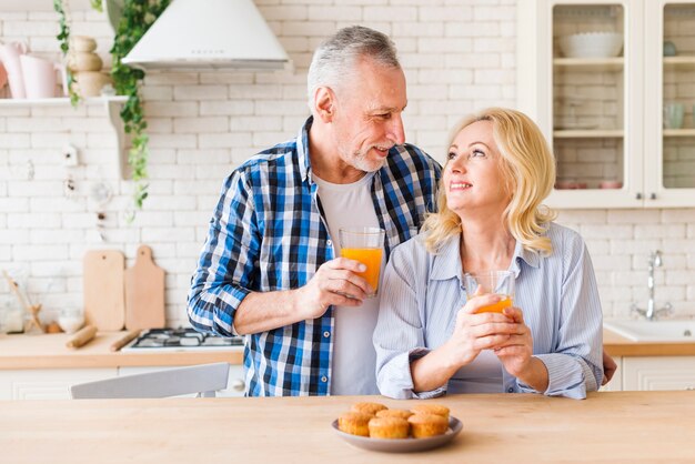 Muffins caseros al horno en la mesa frente a encantadora pareja joven sonriente en la cocina