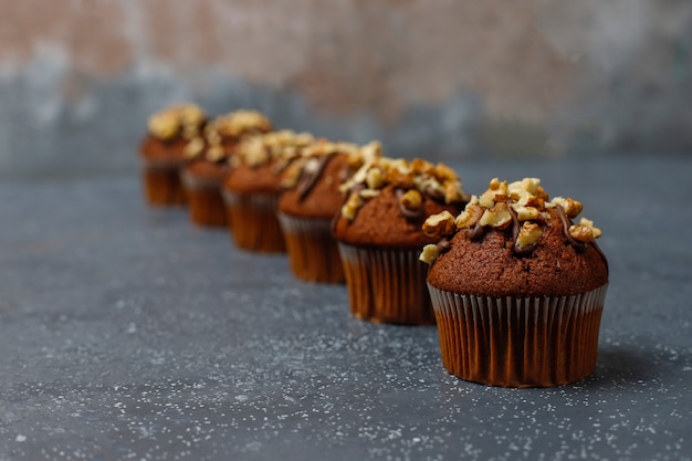 Muffins de chocolate y nueces con una taza de café con nueces sobre una superficie oscura