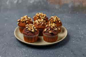 Foto gratuita muffins de chocolate y nueces con una taza de café con nueces sobre una superficie oscura
