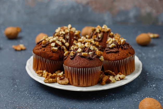 Muffins de chocolate y nueces con una taza de café con nueces sobre una superficie oscura