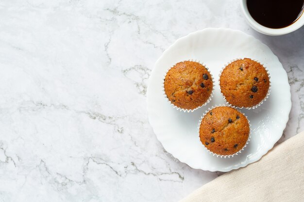 Muffins de chocolate en plato blanco redondo con una taza de café