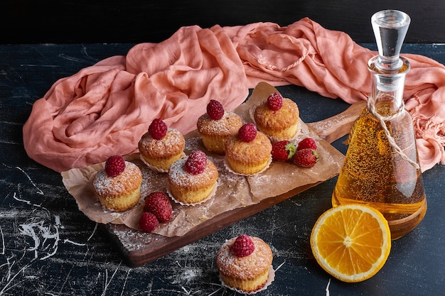 Muffins con frambuesas sobre tabla de madera.