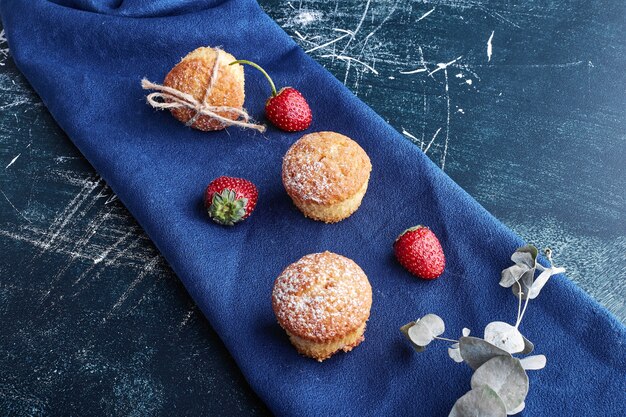 Muffins con fresas sobre una toalla azul.