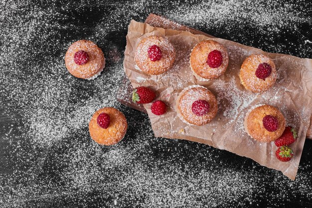 Muffins con frutos rojos en bandeja de madera.