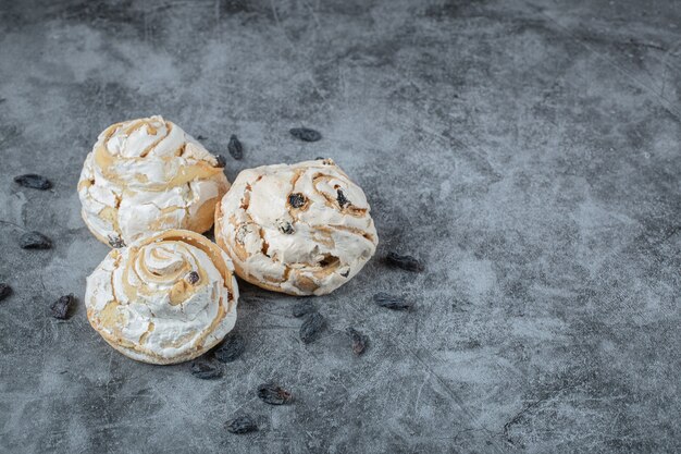 Muffins de merengue esponjoso con uvas negras secas sobre la mesa.