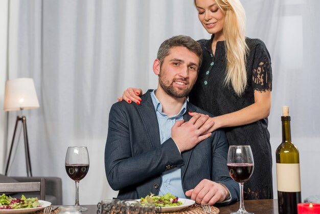 Mujer abrazando al hombre en la mesa con platos y vasos