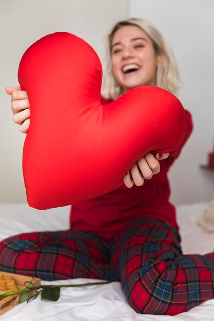 Mujer abrazando la almohada del corazón en el día de San Valentín