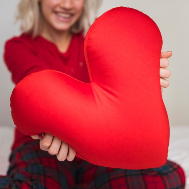 Foto gratuita mujer abrazando la almohada del corazón en el día de san valentín