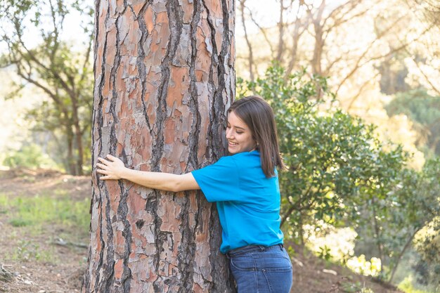 Mujer abrazándose árbol verde en grove